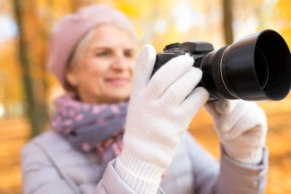 Mulher sênior com câmera de fotos no parque de outono — Fotografia de Stock