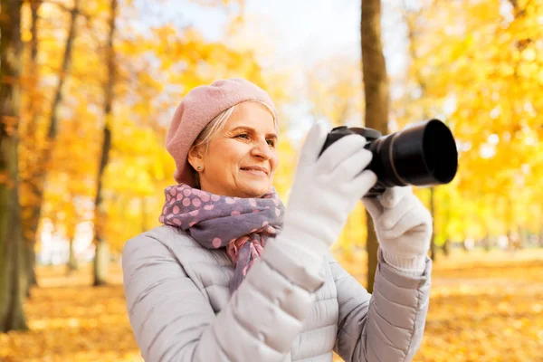 Seniorin mit Fotokamera im Herbstpark — Stockfoto