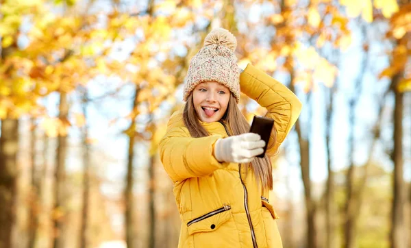 秋の公園でスマートフォンで自分撮りをする女の子 — ストック写真