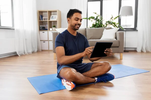 Hombre indio con tableta PC y colchoneta de ejercicio en casa —  Fotos de Stock