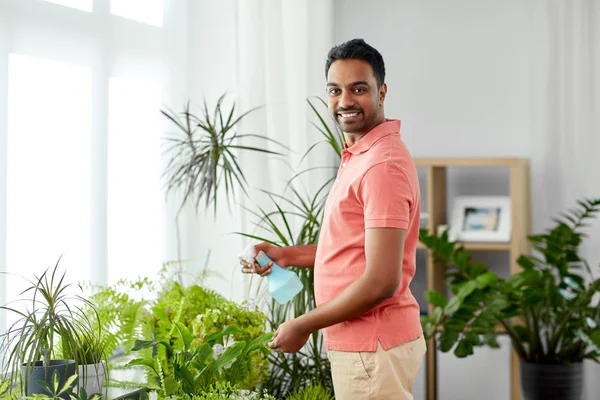 Uomo spruzzando pianta d'appartamento con acqua a casa — Foto Stock