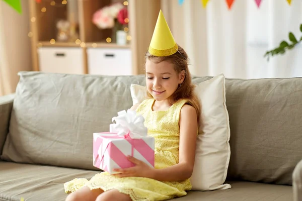 Szczęśliwy dziewczyna w imprezie kapelusz z urodzinowy prezent w domu — Zdjęcie stockowe