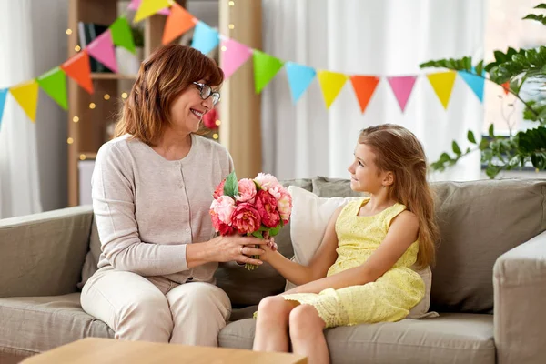Enkelin schenkt Oma Blumen zu Hause — Stockfoto