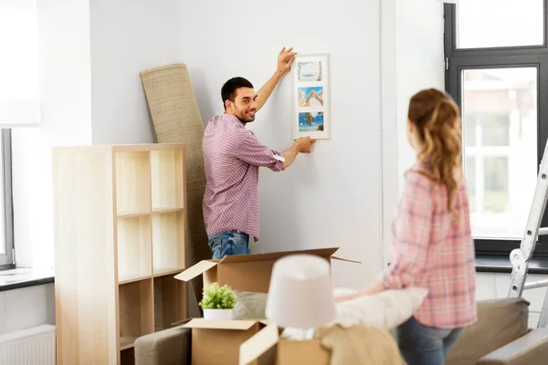 Feliz pareja mudándose a nuevo hogar y colgando foto —  Fotos de Stock