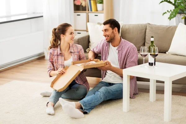 Pareja con vino comer pizza para llevar en casa — Foto de Stock