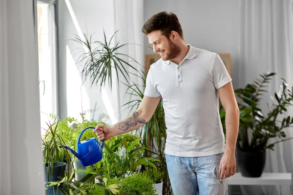 Mann gießt Zimmerpflanzen zu Hause — Stockfoto