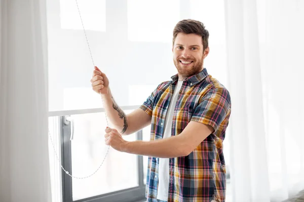 Mężczyzna otwierając roletę na okno w domu — Zdjęcie stockowe