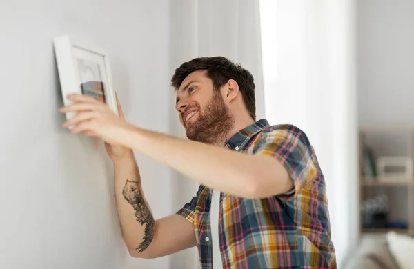 Man opknoping foto in frame aan muur thuis — Stockfoto