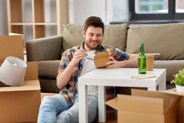 Tersenyum pria makan makanan takeaway di rumah baru — Stok Foto