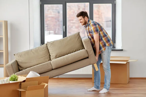 Щасливий чоловік рухає диван в новому будинку — стокове фото