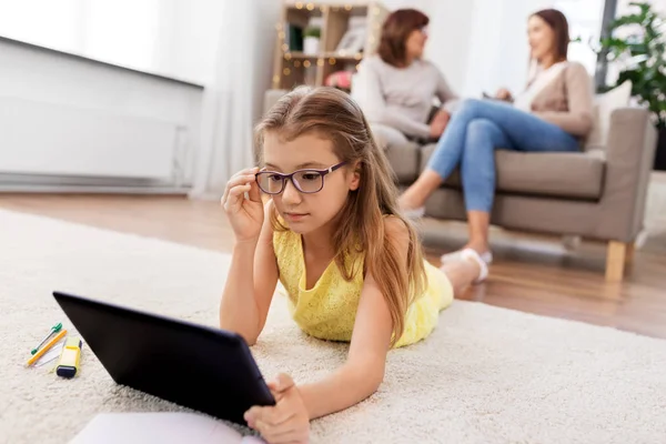 Flicka med Tablet dator liggande på golvet hemma — Stockfoto