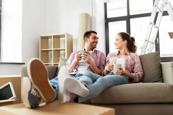 Счастливая пара пьет кофе переезжая в новый дом — стоковое фото