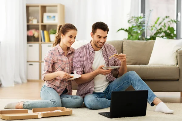 快乐的夫妇带着笔记本电脑在家里吃披萨 — 图库照片