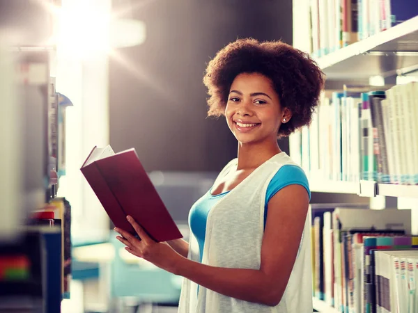 Felice africano studente ragazza lettura libro in biblioteca — Foto Stock