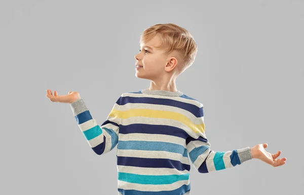 Glimlachende jongen houdt iets op lege handen — Stockfoto