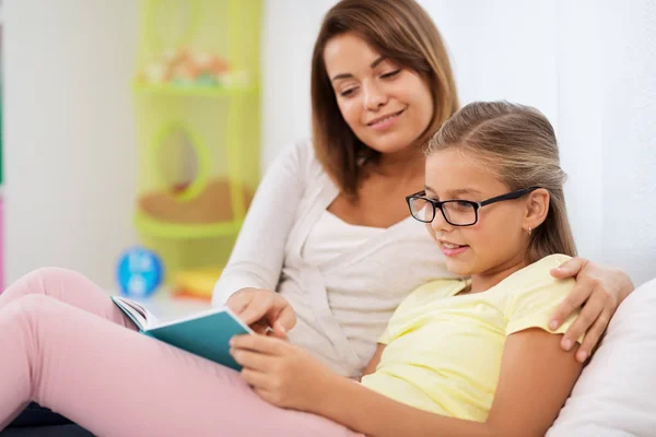 Chica feliz con madre leyendo libro en casa —  Fotos de Stock