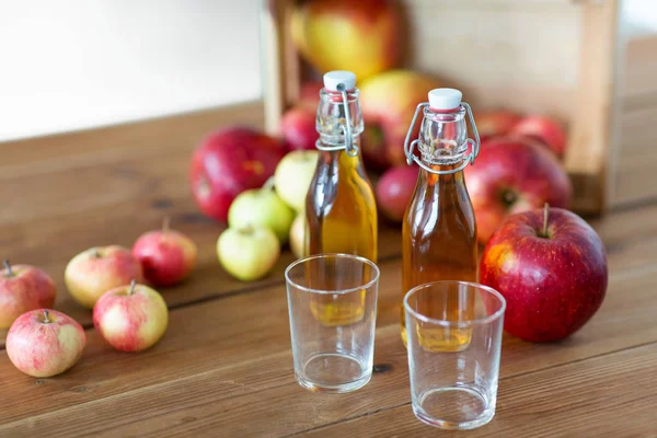 Vasos y botellas de zumo de manzana sobre mesa de madera — Foto de Stock