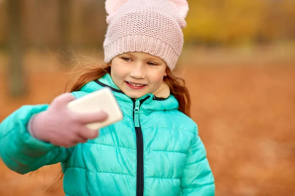 Chica tomando selfie por teléfono inteligente en el parque de otoño — Foto de Stock