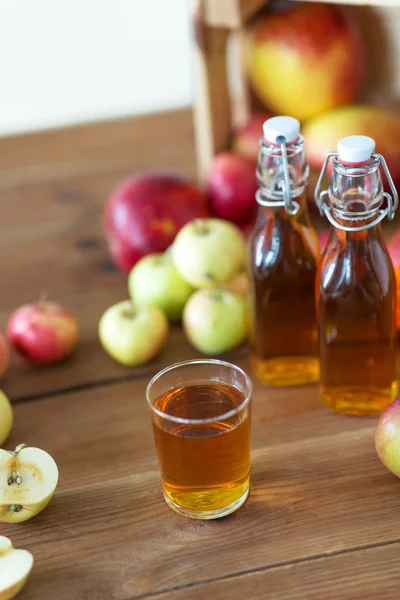 Glas und Flaschen Apfelsaft auf Holztisch — Stockfoto