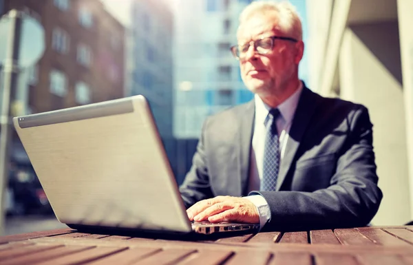 Senior businessman with laptop at outdoor cafe — Stock Photo, Image