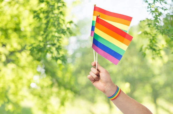 Hand with gay pride rainbow flags and wristband — Stock Photo, Image