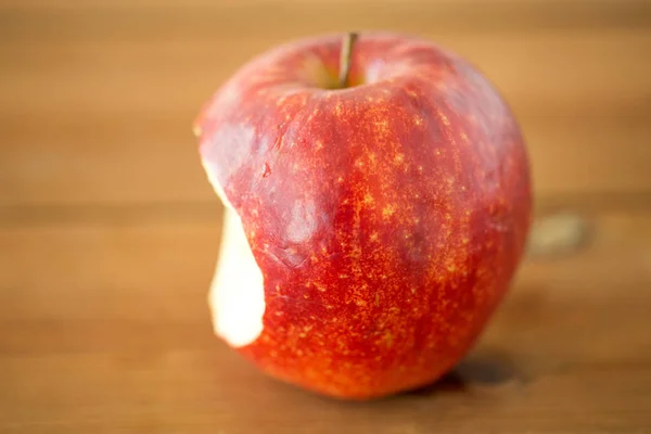 Ώριμο κόκκινο μήλο που δαγκώνει σε ξύλινο τραπέζι — Φωτογραφία Αρχείου