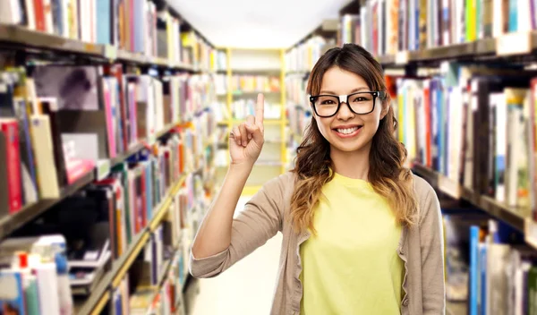 Asiática mulher ou estudante com o dedo para cima na biblioteca Fotografia De Stock