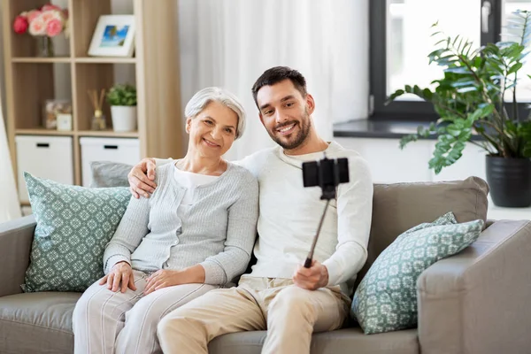 Seniorin mit erwachsenem Sohn macht Selfie zu Hause — Stockfoto