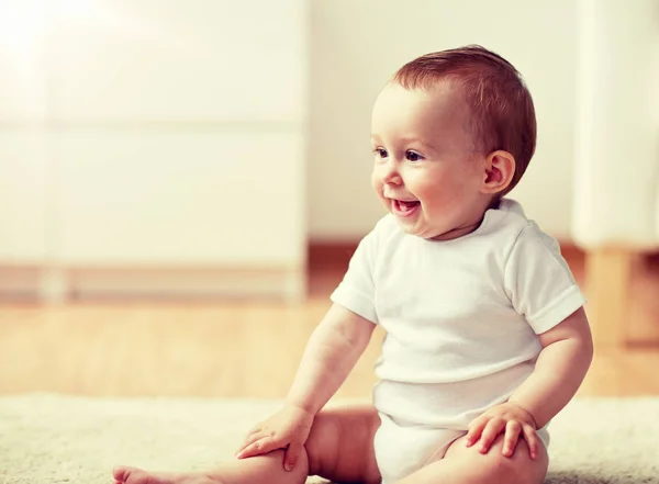 Glad liten pojke eller flicka sitter på golvet hemma — Stockfoto