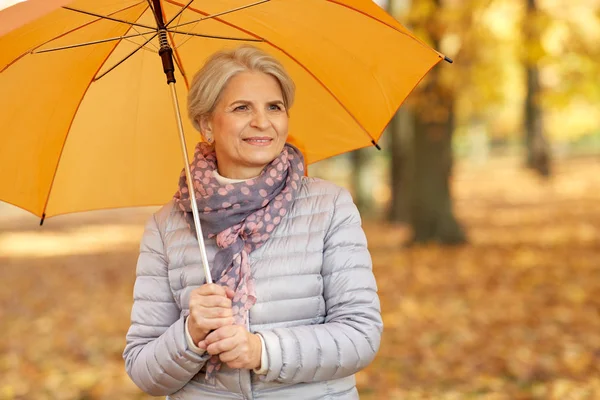 Felice donna anziana con ombrello al parco autunnale — Foto Stock