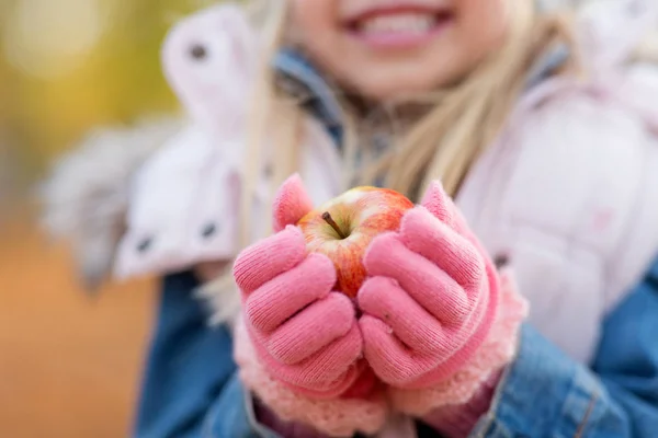 Close up of little girl holding apple in autumn — Stock Photo, Image