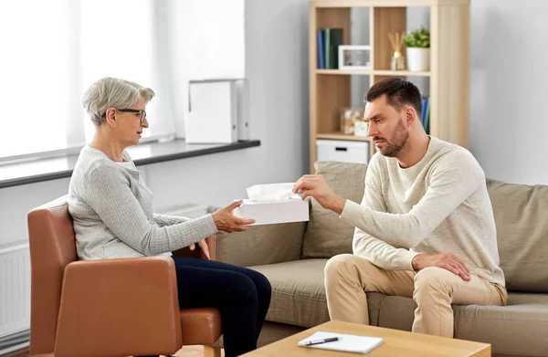 Senior psycholoog geven weefsels aan de mens patiënt — Stockfoto