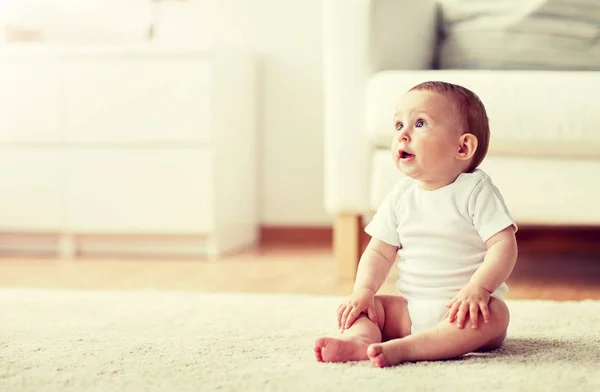 Niño o niña feliz sentado en el suelo en casa Fotos de stock libres de derechos
