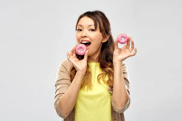 Gelukkig aziatische vrouw eten donuts — Stockfoto