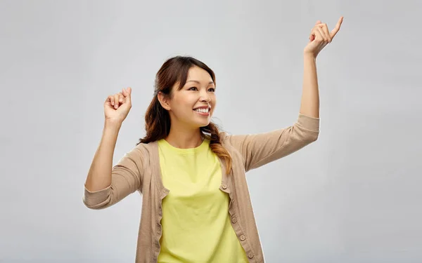 灰色の背景で踊る幸せなアジアの女性 — ストック写真