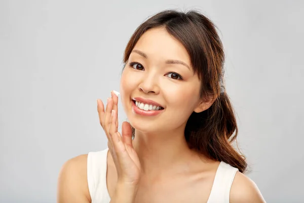 Joven asiático mujer aplicación de crema hidratante a su cara — Foto de Stock
