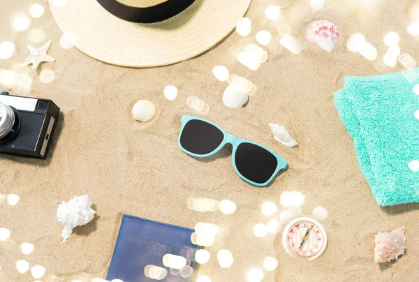 Caméra, passeport, lunettes de soleil et chapeau sur sable de plage — Photo