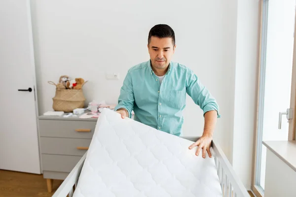 Ojciec układanie łóżeczka z materacem w domu — Zdjęcie stockowe