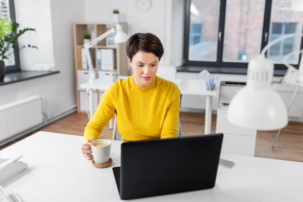 Empresária com laptop bebe café no escritório — Fotografia de Stock