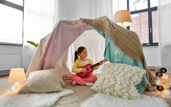 Bambina che suona la chitarra nella tenda dei bambini a casa — Foto Stock