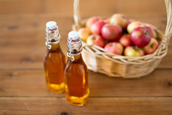 Äpfel im Korb und Saftflaschen auf dem Tisch — Stockfoto