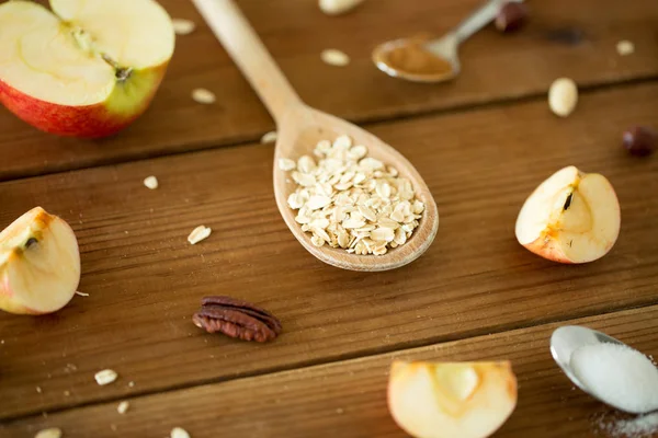 Oatmeal di sendok kayu, apel dipotong dan kacang-kacangan — Stok Foto