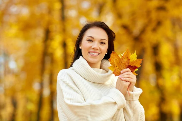 Happy young woman with maple leaves in autumn park — Stock Photo, Image