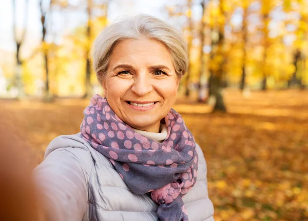 Donna anziana che prende selfie al parco autunnale — Foto Stock