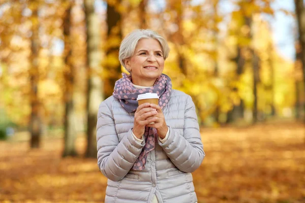 Senior kvinna dricker kaffe i höstparken — Stockfoto