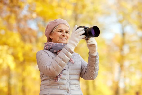 Mulher sênior com câmera de fotos no parque de outono — Fotografia de Stock