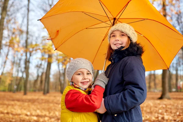 Glückliche Kinder mit Regenschirm im Herbstpark — Stockfoto