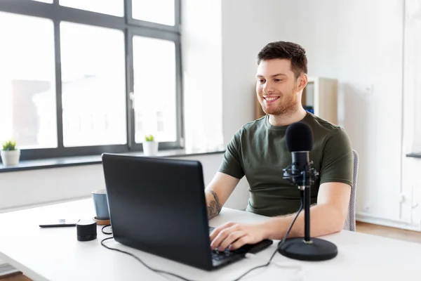 Человек с ноутбуком и микрофоном в домашнем офисе — стоковое фото