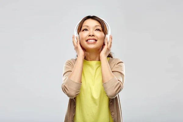 ヘッドフォンで音楽を聴いているアジア系女性は — ストック写真