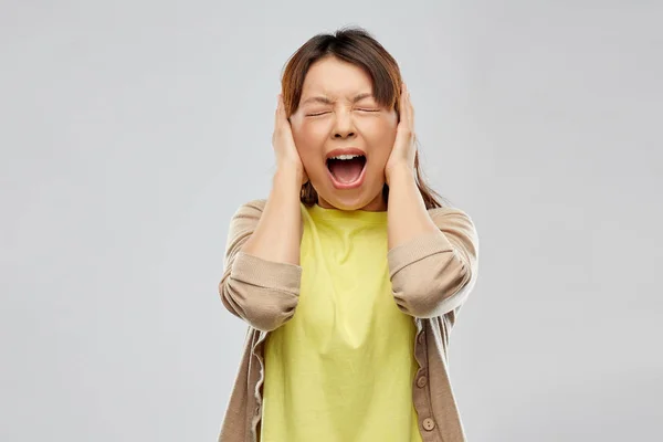 Stressed asian woman closing ears and screaming — Stock Photo, Image